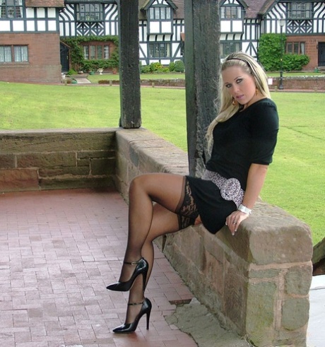 Fully clothed female displays her nylon clad legs in high heels on brick porch 15328560
