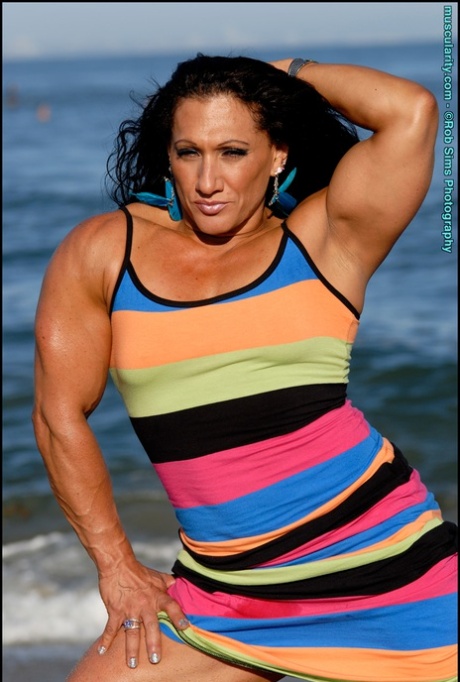 Brunette bodybuilder Tonia Moore flexes her muscles in a dress on the beach 73108296