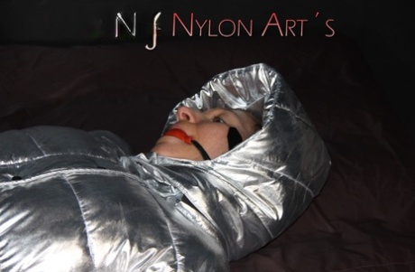 Caucasian girl is tied up in black nylon pants and a silver down jacket 83925932