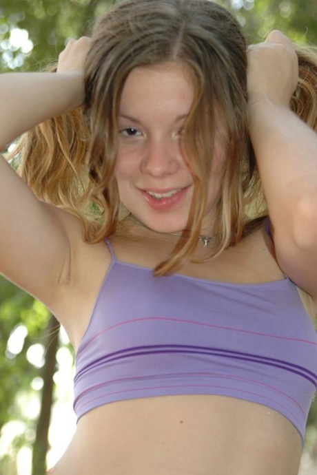 Young looking girl licks her lips while teasing at a park on a picnic table 91662423