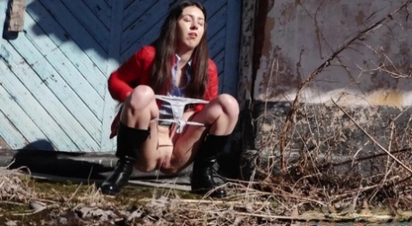 Brunette chick Katya squats for a piss behind a building in black boots 82538435