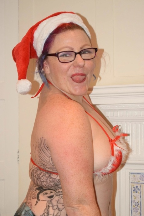Tattooed older woman gets discards a bikini pose nude in a Santa cap 44554965