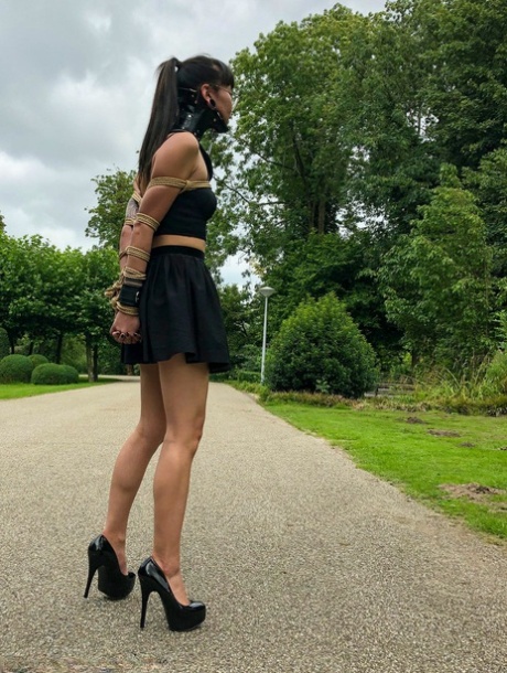 Asian chick Flawless Meow wears a neck collar with her arms bound in a park 29819748